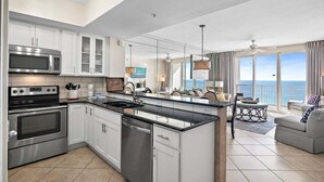 Una cocina moderna con electrodomésticos de acero inoxidable, una isla grande y vistas al océano.