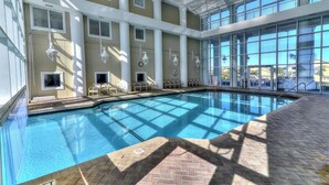 Una piscina interior con paredes de vidrio transparente, suelo de baldosas y techo con tragaluces.
