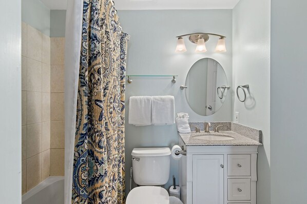 A bathroom with a shower, toilet, sink, and a mirror with lights. - Gulf Views⛱️- Pools-Walk to Restaurants⛱️ Walk to Beach- Wave Whisper🔆 (Miramar Beach)