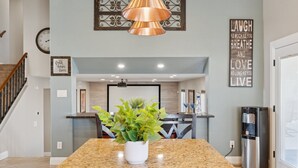 A kitchen with granite countertops, a stainless steel refrigerator, and a potted plant on the island. - The Fritz | Pool + Theater + Games | Sleeps 14 (Glendale)