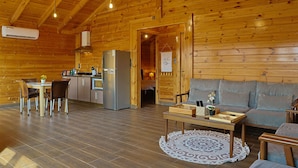 Interior d'una cabana de fusta amb menjador, cuina i saló.