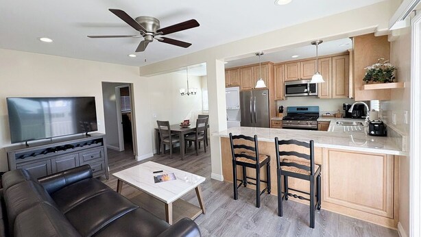 A modern living room with a flat-screen TV, leather sofa, and a dining area with wooden chairs.