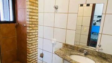 Casa de banho com sanita, lavatório e chuveiro.