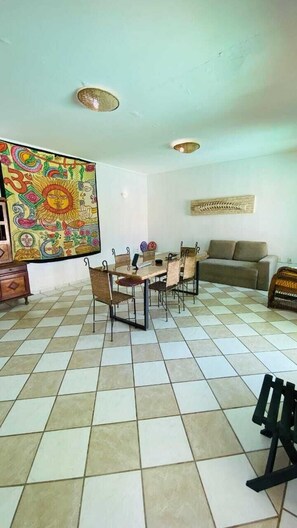 Ein Essbereich mit Tisch und Stühlen, einer Couch und einem farbenfrohen Wandbild.