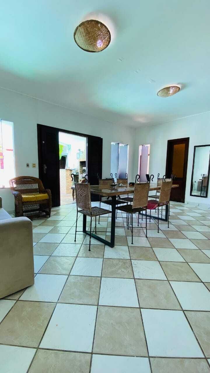 A dining area with a table and chairs, a wicker ceiling light, and a tiled floor.