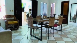 Un comedor con una mesa y sillas, una lámpara de techo de mimbre y un piso de baldosas.