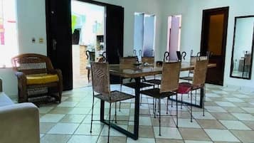 A dining area with a table and chairs, a wicker ceiling light, and a tiled floor.