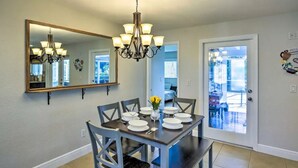 A dining area with a chandelier, a large mirror, and a table set for six. - Tropical Getaway! Gulf access with heated pool! (Cape Coral)