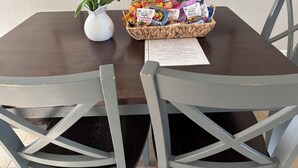 A table with a white vase of yellow flowers, a basket of snacks, and a menu. - Tropical Getaway! Gulf access with heated pool! (Cape Coral)