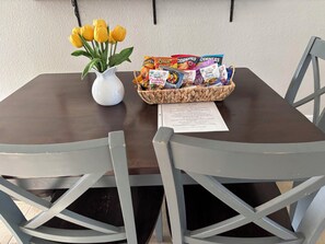 A table with a white vase of yellow flowers, a basket of snacks, and a menu.