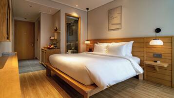 A modern hotel room with a wooden bed, a bedside table, a nightstand, and a mirror.