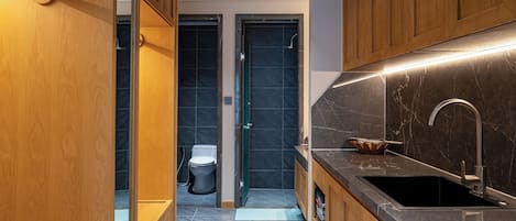 A modern kitchen with wooden cabinets, a black countertop, and a stainless steel sink.