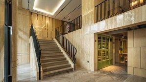 A modern hotel lobby with a marble staircase, a glass door entrance, and a herringbone-patterned floor. - Nam Dat Hotel by D'Lecia Ha Long (Hong Gai)