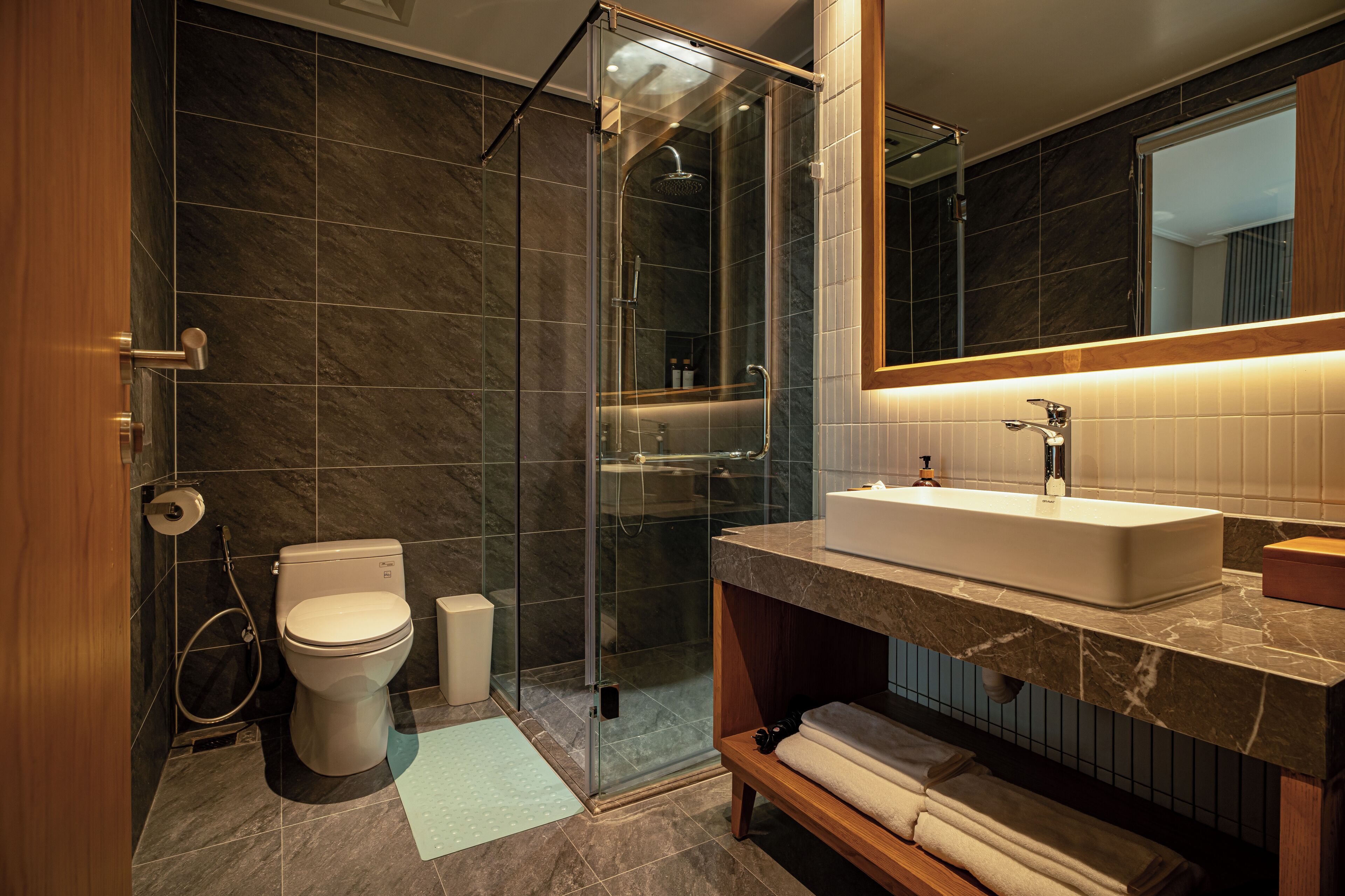 Une salle de bain moderne avec une douche à parois de verre, un lavabo blanc et un grand miroir.