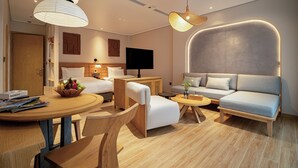 A modern living room with a sofa, armchairs, a coffee table, and a dining table. There is a television and a bookshelf in the background. - Nam Dat Hotel by D'Lecia Ha Long (Hong Gai)