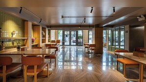 A spacious cafe with wooden furniture, large windows, and a polished floor. - Nam Dat Hotel by D'Lecia Ha Long (Hong Gai)