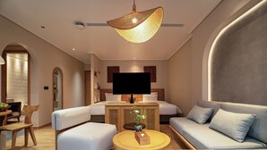 A modern hotel room with a sofa, a bed, a TV, and a dining area with a table and chairs. - Nam Dat Hotel by D'Lecia Ha Long (Hong Gai)