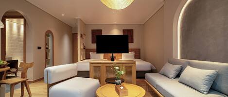 A modern hotel room with a sofa, a bed, a TV, and a dining area with a table and chairs.