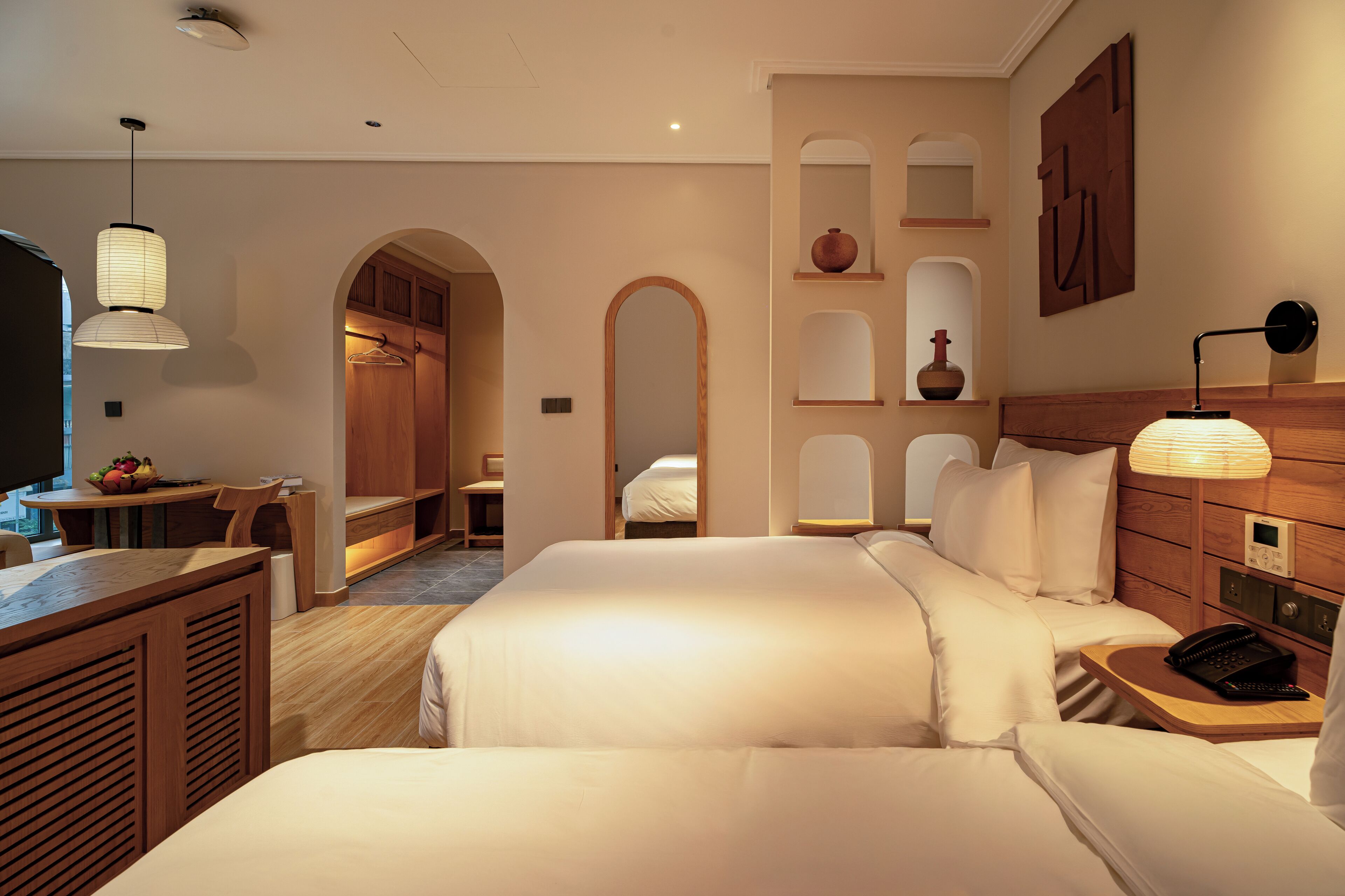 A hotel room with a large bed, bedside tables, a desk, and a seating area.