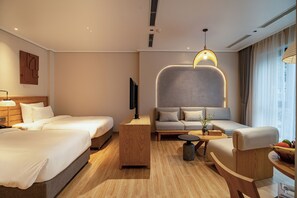A modern hotel room with two beds, a sofa, a coffee table, and a TV. - Nam Dat Hotel by D'Lecia Ha Long (Ha Long)