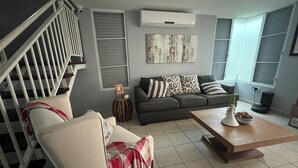 A modern living room with a staircase, grey sofa, and a coffee table.
