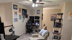 A home office with a desk, chair, computer, and various posters on the walls. - Masters Rental - Walking Distance + WFH Spaces! (Augusta)