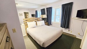 Een netjes ingerichte hotelkamer met een groot bed, een televisie, een bureau en een raam met gordijnen.