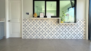 Un área de recepción con una pared con diseño, una ventana con vistas, un letrero que dice 'Tocar' y un aviso enmarcado.