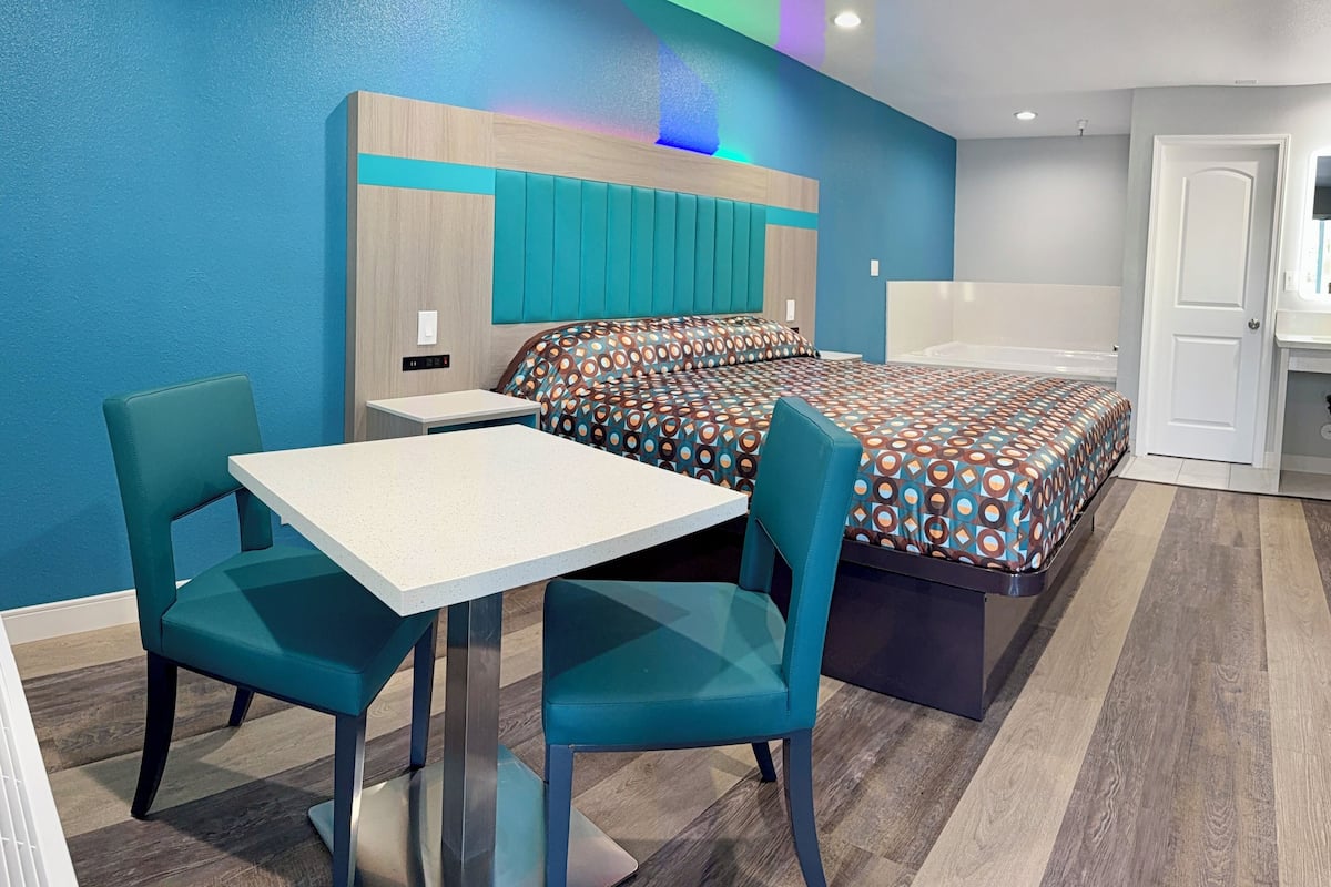 A modern hotel room with a bed, a desk, and two chairs.