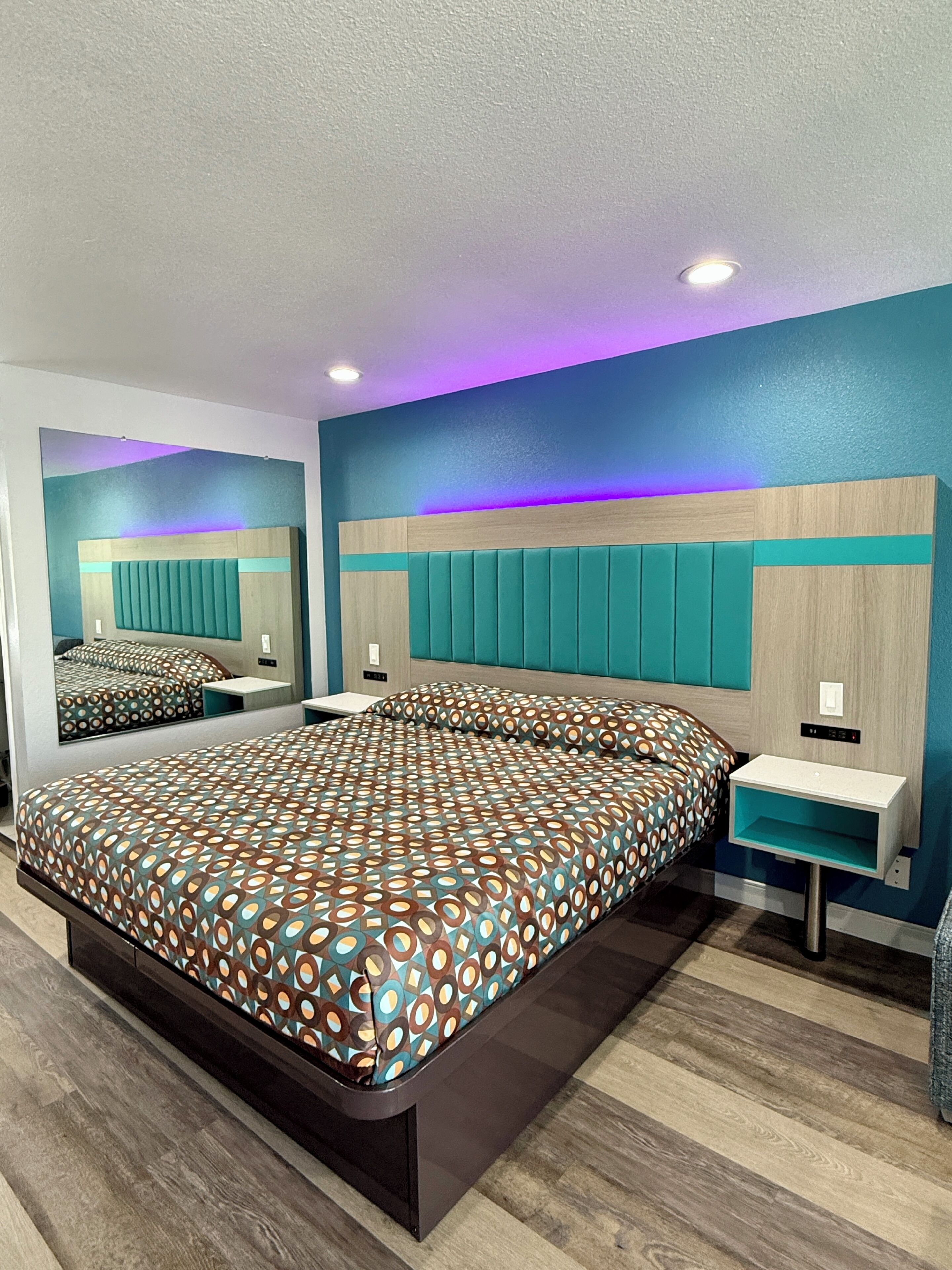 Un dormitorio moderno con una cama grande, una mesita de noche, un espejo y una cabecera empotrada.