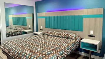 Un dormitorio moderno con una cama grande, una mesita de noche, un espejo y una cabecera empotrada.