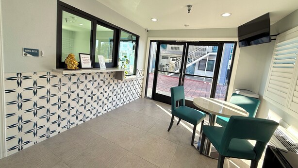 Un área de recepción con pared de azulejos, un mostrador de recepción, una ventana y dos sillas.