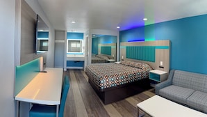 Una habitación de hotel moderna con una cama grande, un sofá, un escritorio y un televisor.