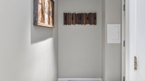 A hallway with a wooden wall art piece and a door. - Charming Stay in Stowe Condo: Hot Tub&Indoor Pool (Stowe)