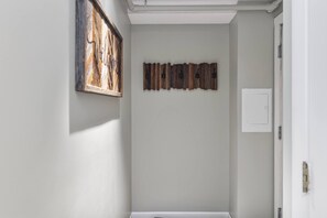 A hallway with a wooden wall art piece and a door.