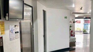 Ein Flur mit Kühlschrank, Feuerlöscher und einer Tür mit Notausgangsschild.