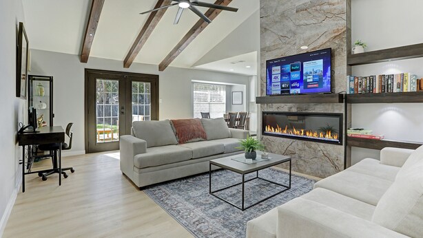 A modern living room with a fireplace, a ceiling fan, and a mounted TV. - NEW Charming 3BR 2BA w/Modern Fireplace by Domain @ Q2 Stadium (Austin)