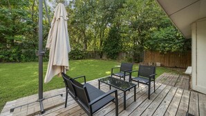 A wooden deck with outdoor furniture, including chairs and a table, and a covered umbrella. - NEW Charming 3BR 2BA w/Modern Fireplace by Domain @ Q2 Stadium (Austin)