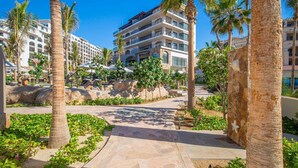 Ein Resort mit mehrstöckigen Gebäuden, Palmen und einem gepflasterten Weg.