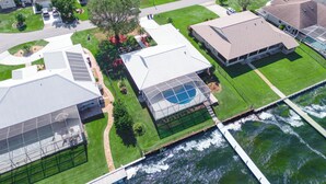 An aerial view of a residential area with houses, a swimming pool, and a bridge over a river.