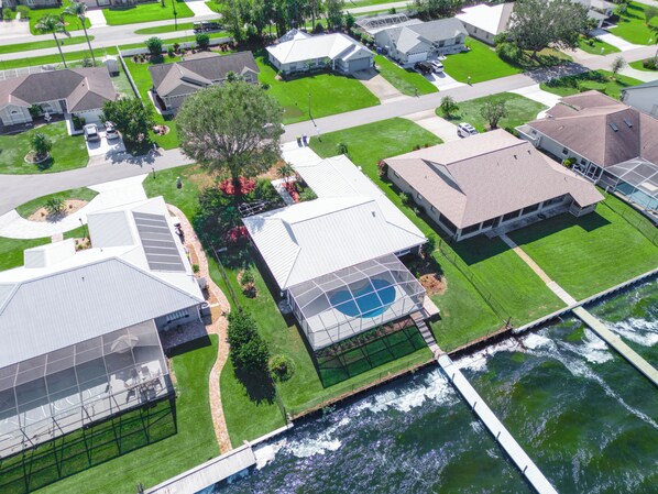 An aerial view of a residential area with houses, a swimming pool, and a bridge over a river.