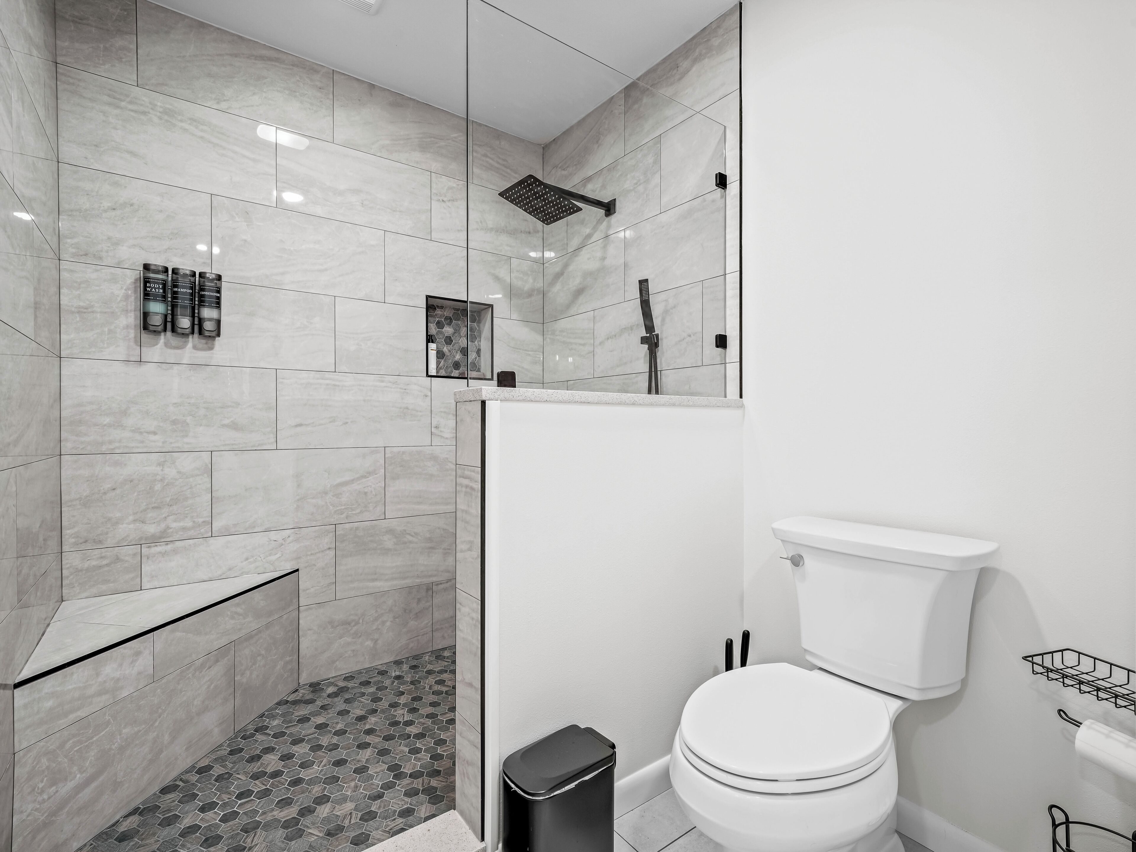 A modern bathroom with a shower, toilet, and a tiled floor.