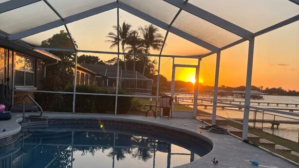 A pool area with a fire feature and a view of the sunset.