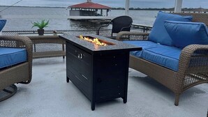A covered outdoor seating area with wicker furniture and a black grill table.