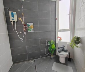 A bathroom with a shower, toilet, and a potted plant.