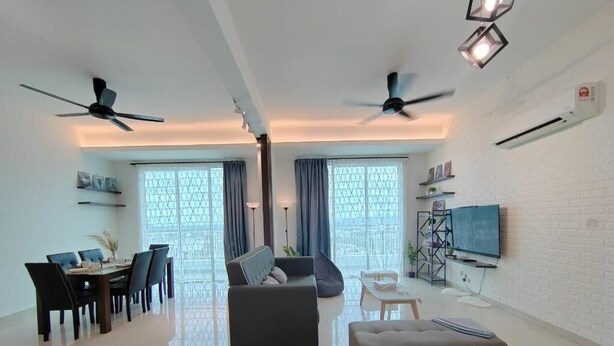 Ein modernes Wohnzimmer mit Essbereich, zwei Deckenventilatoren, einem Flachbildfernseher und einer weißen Ziegelwand.