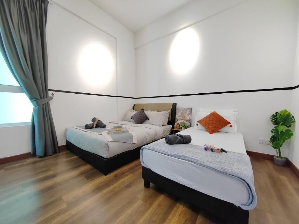 A bedroom with two beds, a potted plant, and a window with curtains.