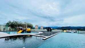 Ein Dachpool mit Infinity-Kante, Wasserrutsche und Blick auf ferne Berge.