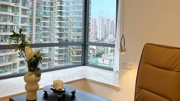 A modern room with a large window, a vase with flowers, a small table, and a brown chair.