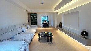 A modern living room with a sofa, a coffee table, and a dining area in the background. - Eastern Hub - Superior 3bedroom Near TianZiFang&XinTianDi, Near Subway (shanghai)